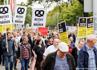 Germany: will bread soon cost ten euros? | Germany | DW Men and women in everyday clothes walk through the city center of Hanover on a train. Several demonstrators hold up signs reading Save us bakers.