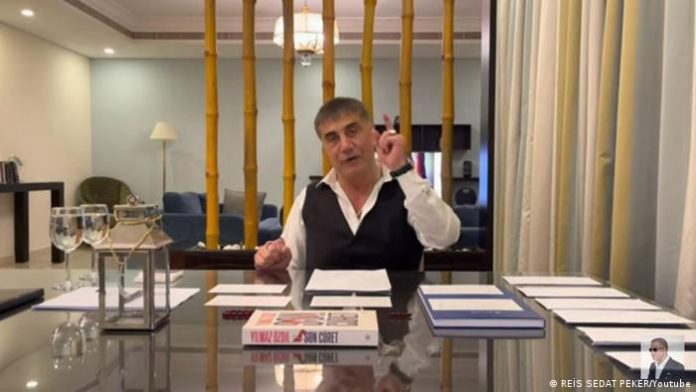 Screenshot Youtube |  Mafia boss Sedat Peker at a table in a room reminiscent of a luxurious hotel suite