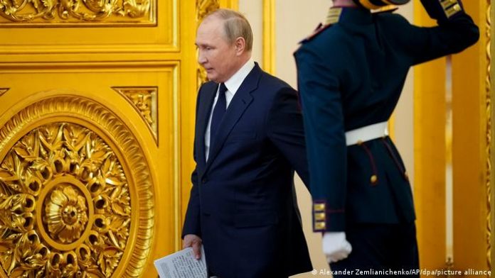 Russian President Vladimir Putin walks through a golden door in the Kremlin, a security guard salutes