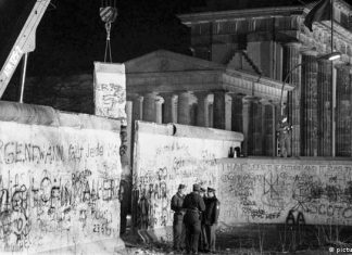 Germany-wide open-air singing for peace | music | DW Opening of the Wall at the Brandenburg Gate: Police officers from East and West Berlin talk at the Brandenburg Gate while a piece of the Wall is being lifted up behind them with a crane